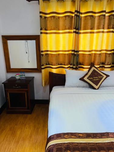 a bedroom with a bed with a yellow curtain and a window at Vang vieng guesthouse in Vang Vieng