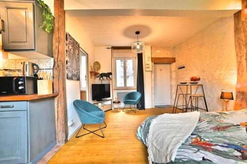 Il comprend une chambre avec un lit et une cuisine avec des chaises. dans l'établissement Jungle Rochelaise - Coeur de ville, Entièrement Rénovée, Tv 4K, Fibre, Quartier Porte Royale, à La Rochelle