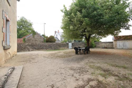 a table and chairs under a tree in a yard at La Chaussée de l'Etang in Marcenay