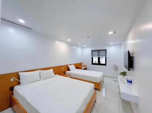 a hotel room with two beds and a tv at Bay Homestay in Cam Lâm