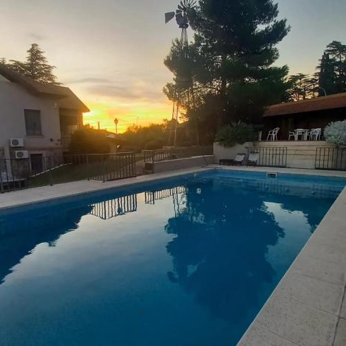 a swimming pool with a sunset in the background at Posada Spa Anabela in Huerta Grande