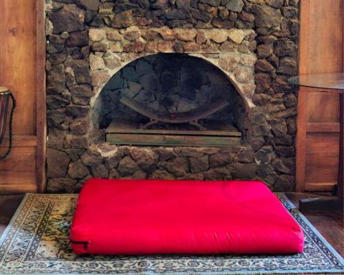 a red pillow in front of a stone fireplace at Warung Rekreasi Bedugul in Bedugul