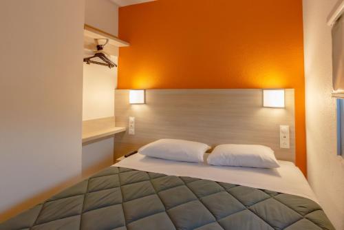 a bedroom with a bed with an orange wall at Première Classe Plaisir Gatines in Plaisir