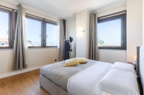 a bedroom with a bed with two pillows and windows at Moderno Attico con Vista Panoramica e Piscina in Turin