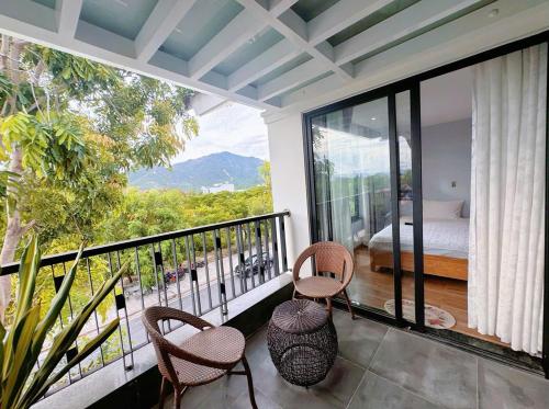 a room with a balcony with a bed and chairs at Bay Homestay in Cam Lâm