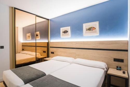 a bedroom with two beds and a mirror at Alda Don Carlos in Santander