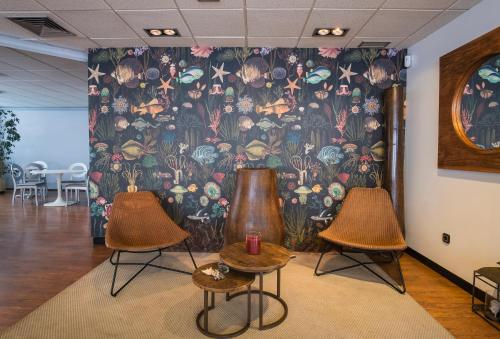 a room with two chairs and a wall with a mural at Alda Don Carlos in Santander