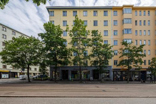 a large yellow building with trees in front of it at Bright 1BR apartment in Kallio with best location in Helsinki