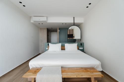 a bedroom with a large white bed and a wooden bench at Paralos The Maxine Adults Only in Agia Galini