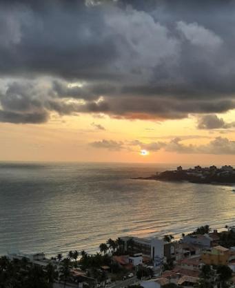 a sunset over the ocean with a city and buildings at Corais de Cotovelo in Parnamirim