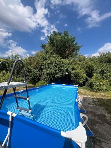 - une piscine bleue avec une chaise à côté dans l'établissement Happy House - 1h30 de Paris, à Batilly-en-Gâtinais