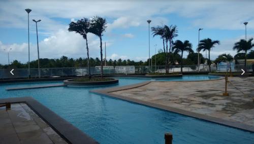 a swimming pool with blue water and palm trees at Corais de Cotovelo in Parnamirim