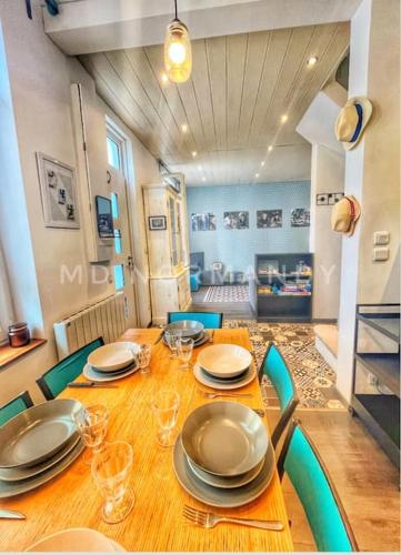 une table de salle à manger avec des assiettes et des verres dessus dans l'établissement Maison centre Villerville, à Villerville