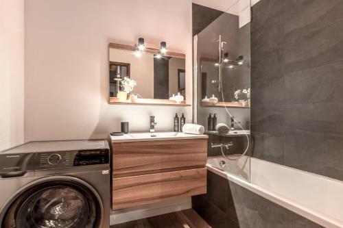 une salle de bain avec une machine à laver et un lavabo dans l'établissement Cristal des Glaces - Balcon avec vue imprenable, à Chamonix-Mont-Blanc