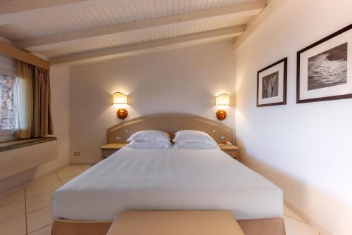 a bedroom with a large white bed with two pillows at Hotel & SPA des Pecheurs in Bonifacio