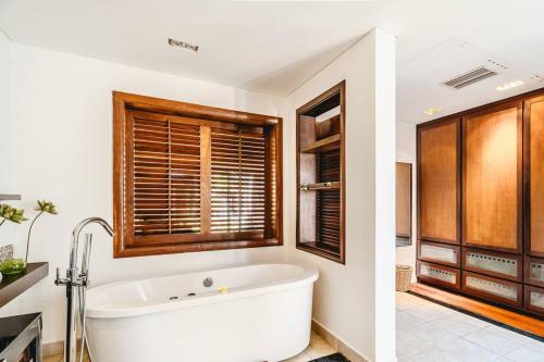 a bathroom with a white tub and a window at Villa Sea View by IHR in Bel Ombre