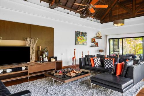 a living room with black leather furniture and a flat screen tv at Villa Sea View by IHR in Bel Ombre