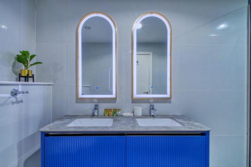 a bathroom with two sinks and two mirrors at GlobalStay Royal Bay Beachfront Apartments Palm Jumeirah in Dubai