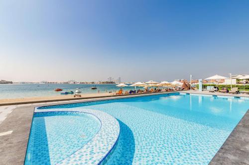 a large swimming pool next to a body of water at GlobalStay Royal Bay Beachfront Apartments Palm Jumeirah in Dubai