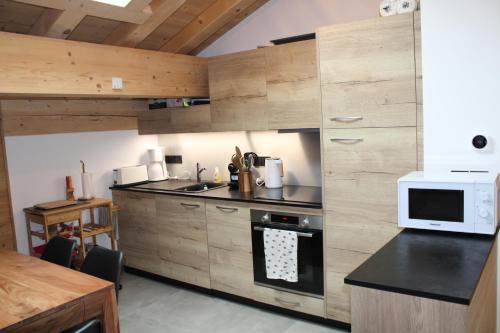 - une cuisine avec des placards en bois et un four micro-ondes dans l'établissement Appartement de standing Chalet Bostan, à Samoëns