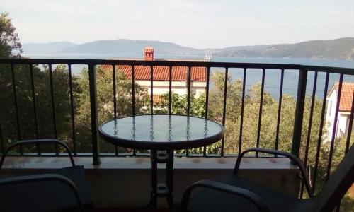 a table on a balcony with a view of the water at Apartment Griv in Valun