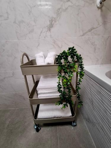 a towel cart in a bathroom with towels and a plant at Happy Studio Luxury Pipera in Voluntari