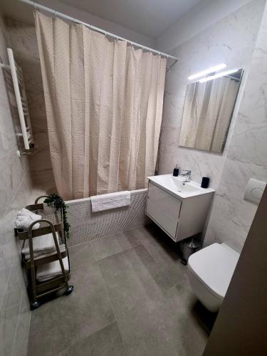 a bathroom with a white toilet and a sink at Happy Studio Luxury Pipera in Voluntari
