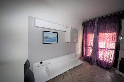 a bathroom with white walls and purple curtains at Lovely 3 room flat in Rosolina with shared pool in Rosolina Mare