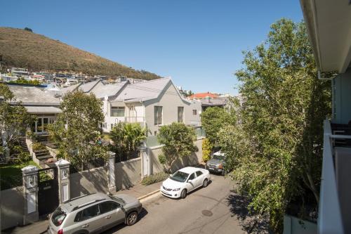 two white cars parked on a street with houses at Home for 8 in central Green Point in Cape Town