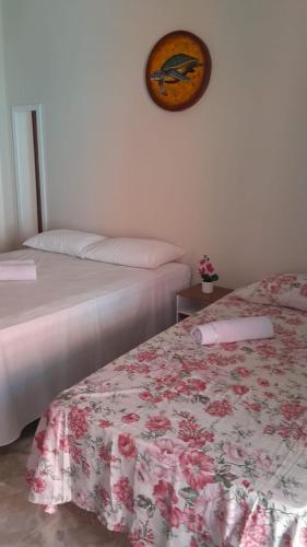 a bedroom with two beds and a clock on the wall at Pousada Flor da Barra in Maragogi