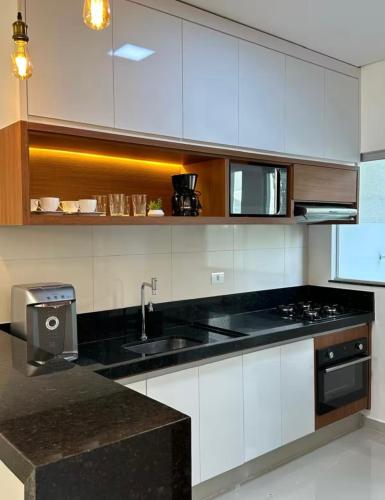 a kitchen with white cabinets and a black counter top at Concierge House Exclusiva in Marabá