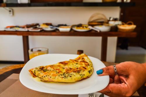 a person holding a slice of pizza on a plate at Morena Jambo in Arraial d'Ajuda