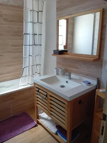 une salle de bain avec un lavabo, un miroir et une baignoire dans l'établissement maison de famille bord mer doublon, à Sarzeau