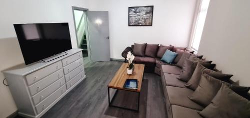 a living room with a couch and a flat screen tv at Large Victorian House 15 minutes from City Centre in Manchester