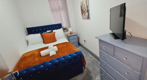 a bedroom with a blue bed and a television at Large Victorian House 15 minutes from City Centre in Manchester