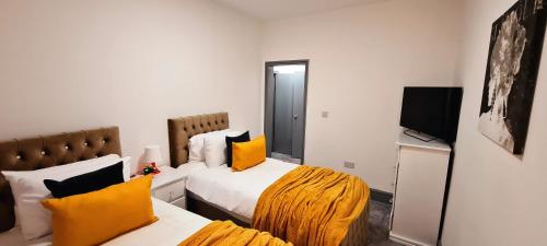 a hotel room with two beds and a flat screen tv at Large Victorian House 15 minutes from City Centre in Manchester