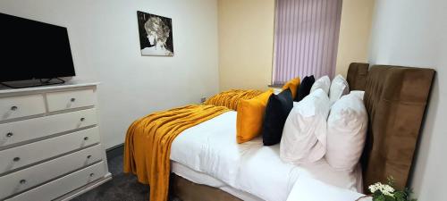 a bedroom with a bed with pillows and a television at Large Victorian House 15 minutes from City Centre in Manchester