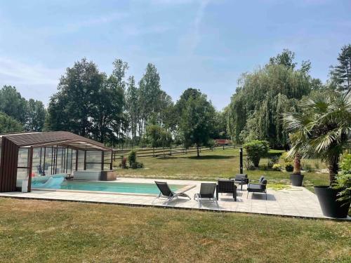 une piscine avec des chaises et un gazebo dans l'établissement logement au coeur de la nature, à Le Grand-Lucé