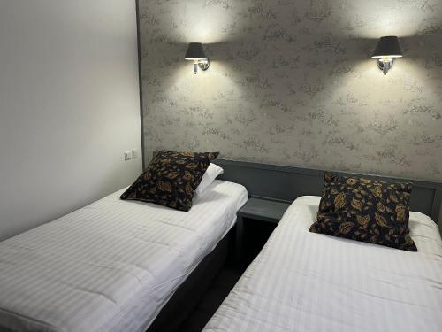two beds in a room with lights on the wall at Hotel Val Saint Hilaire in Givet