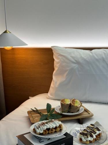 two plates of pastries and cups on a bed at Gurida Bupyeong in Incheon