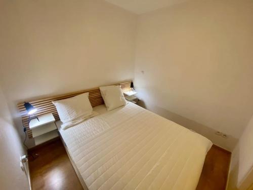 - une petite chambre avec un lit blanc et 2 oreillers dans l'établissement T2 cosy, vue montagne et village, à Allos