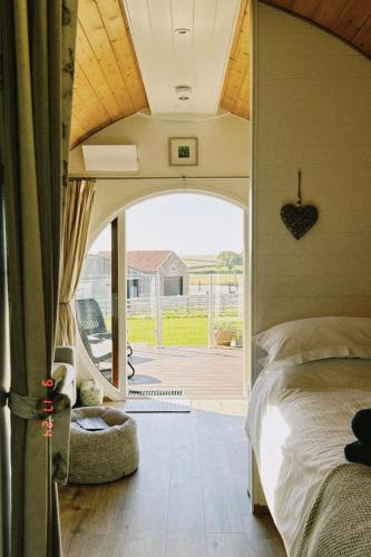 a bedroom with a bed and a door to a yard at Hundle Dale- Bugthorpe Grange Glamping in Stamford Bridge