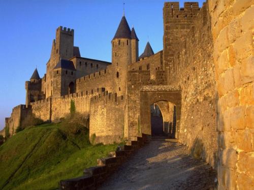 un vieux château avec une arche au premier plan dans l'établissement Séjour Cité, à Carcassonne