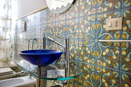 a bathroom with a blue bowl on a glass sink at Sealight Villa Lipari - Vista e Piscina in Lipari