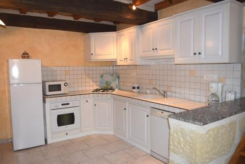 a kitchen with white cabinets and a white refrigerator at Maison ancienne à Puymiclan - Clévacances 3 clés in Puymiclan