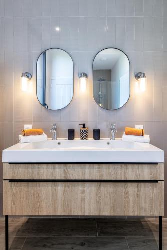 une salle de bain avec deux lavabos et deux miroirs dans l'établissement Villas Goarem Louzet, à Tréméoc