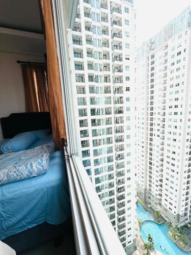 a bedroom with a bed and a window with tall buildings at Emaar Moslem Friendly Stunning Comfy 2BR Apartment at the heart of Jakarta in Jakarta