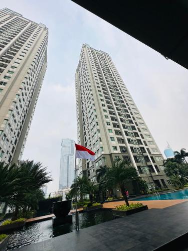 two tall buildings with palm trees in front of them at Emaar Moslem Friendly Stunning Comfy 2BR Apartment at the heart of Jakarta in Jakarta