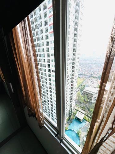 a window with a view of a large building at Emaar Moslem Friendly Stunning Comfy 2BR Apartment at the heart of Jakarta in Jakarta