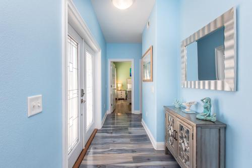 a hallway with blue walls and a mirror and a dresser at Casa Azul - 4B Beach Home in Pensacola Beach